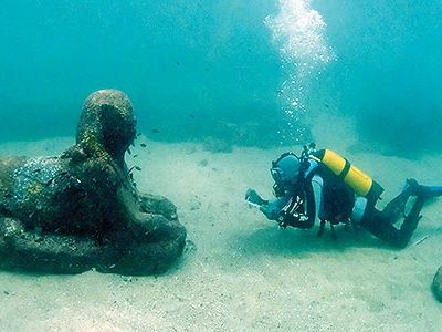 A member of an underwater archaeology team inspects a sphinx that is at least 3,000 years old.