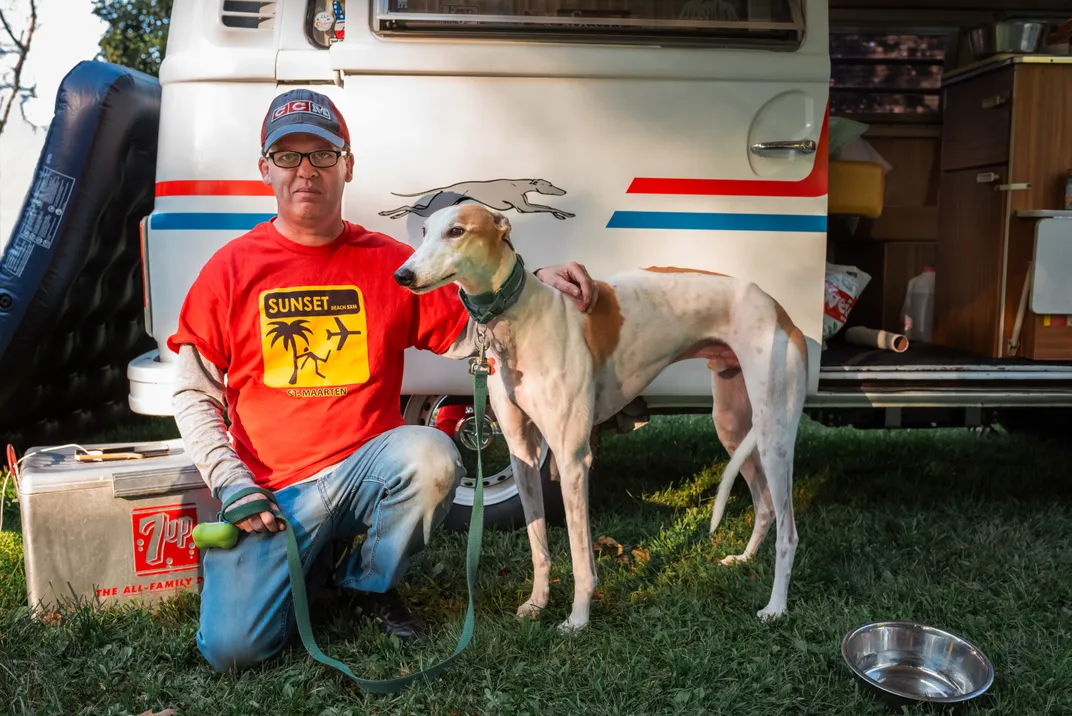 3 -An actual greyhound poses near a vintage Volkswagen with a greyhound decal. The likeness is uncanny.