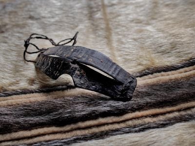 Inupiaq goggles carved from baleen set against a Tunumiit (East Greenland Eskimo) woman’s sealskin parka. Both are from the collection of the National Museum of the American Indian.