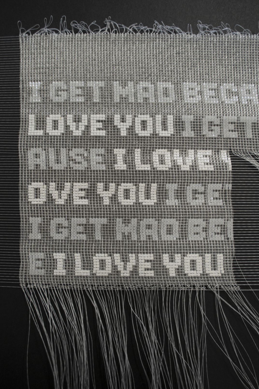 bead art with strings repeating the words "I get mad because I love you"