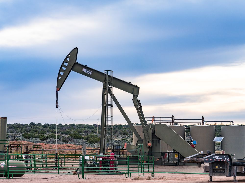 A conventional horsehead oil well pump jack unit and storage tank battery on an oil well site in Utah