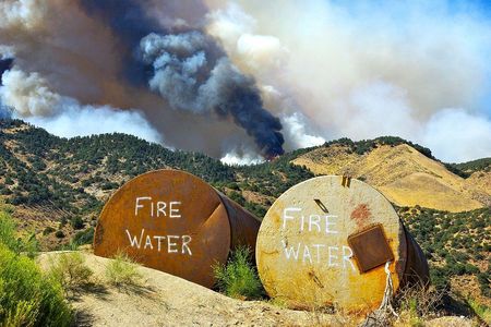 Tanks filled with water await possible use as a fire burns on the crest of a hill in Lebec, California, 2010