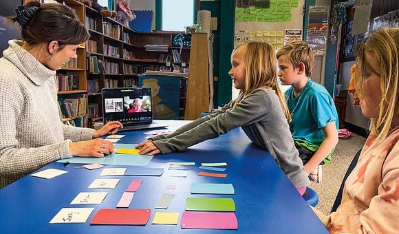 a classroom of students take instructions from their teacher