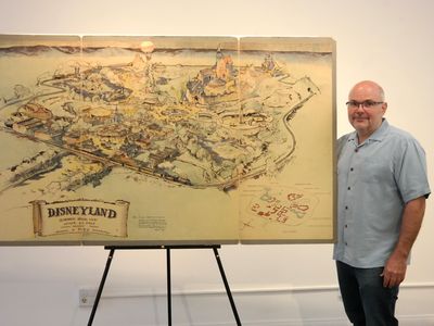 Mike Van Eaton of Van Eaton Galleries, posing with Disney's early map of Disneyland
