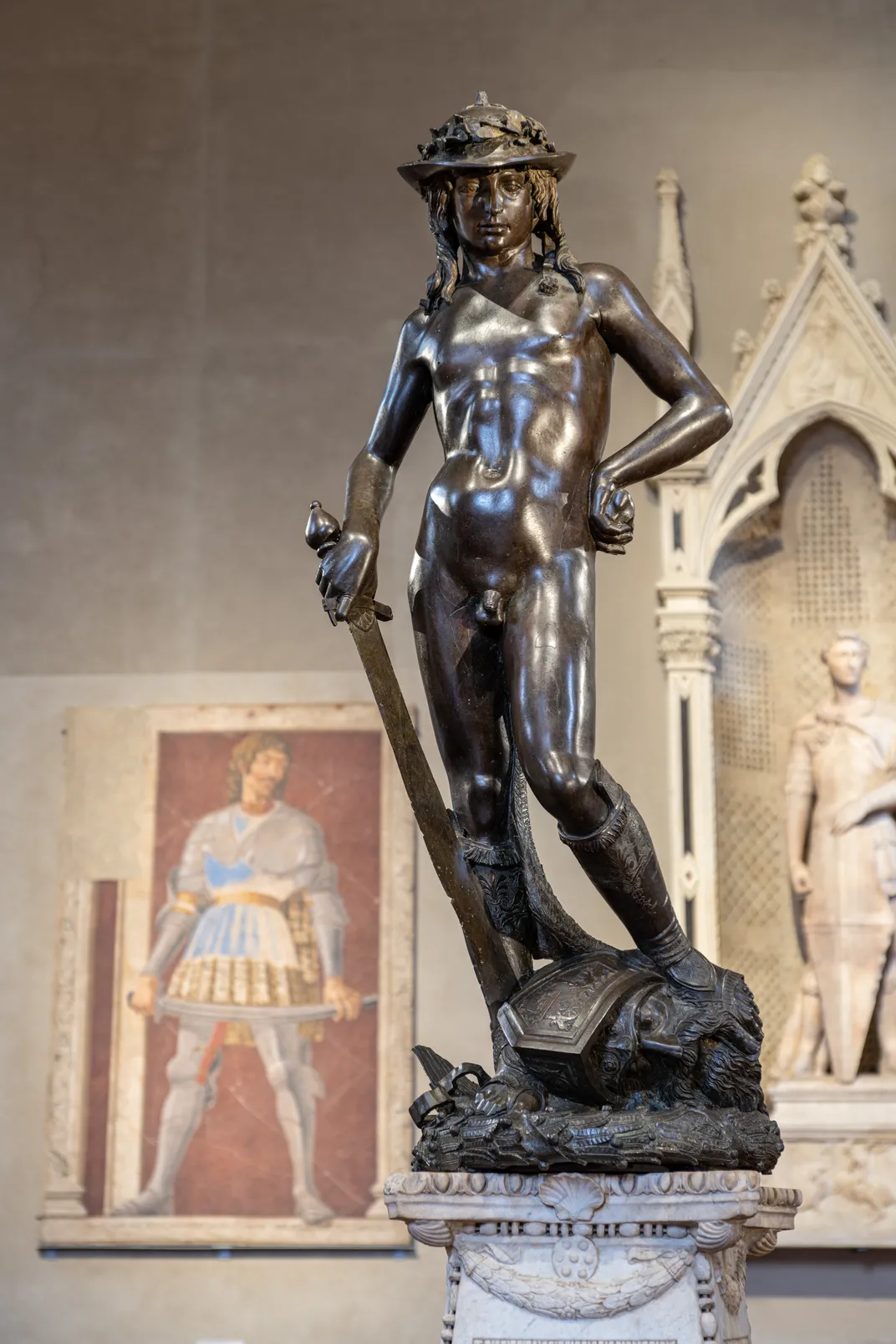 A bronze statue of a young man standing triumphantly on the head of Goliath
