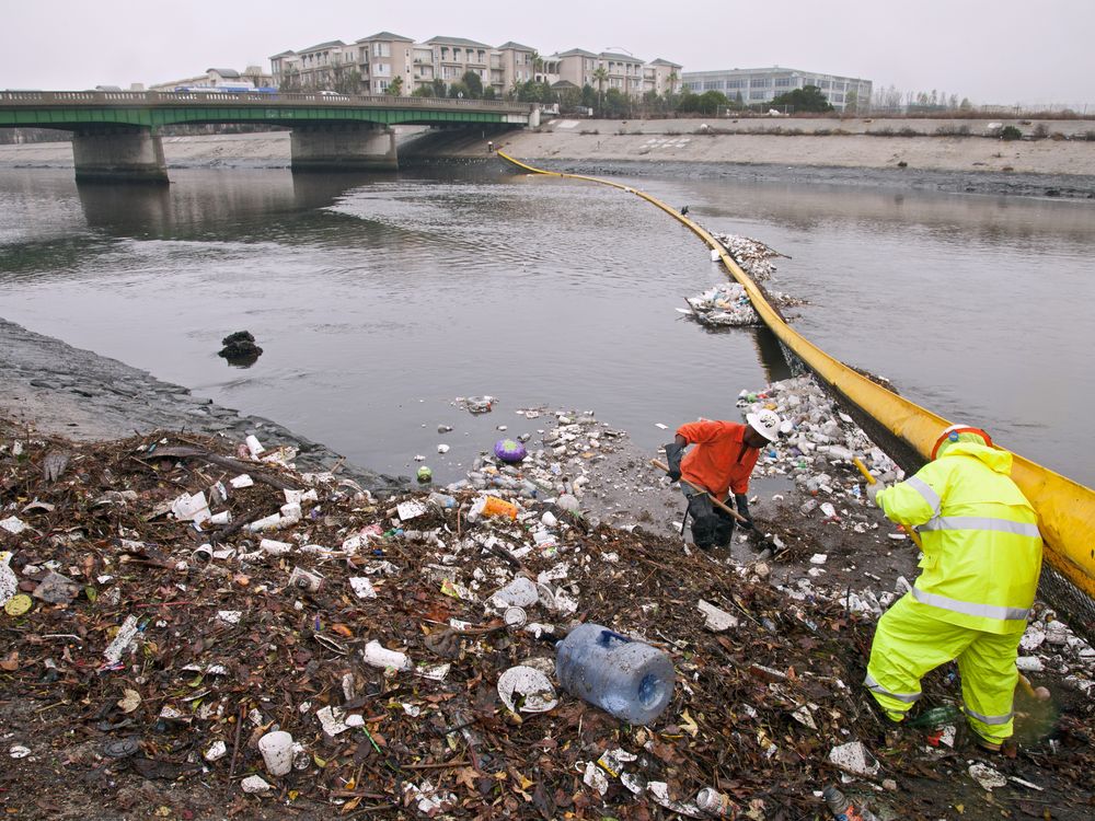 Trash in a river is getting picked up by two workers