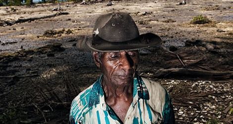 Posakei Pongap, a Manus islander, in front of a field ruined by salinization.