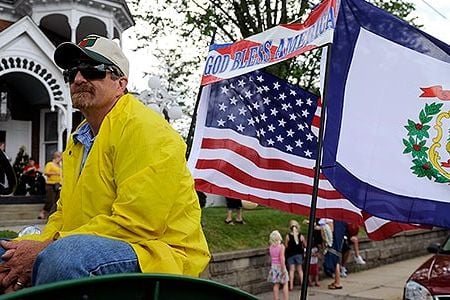 A tractor with the West Virginia flag attached to the back makes it way down Main Street in Buckhannon, West Virginia.