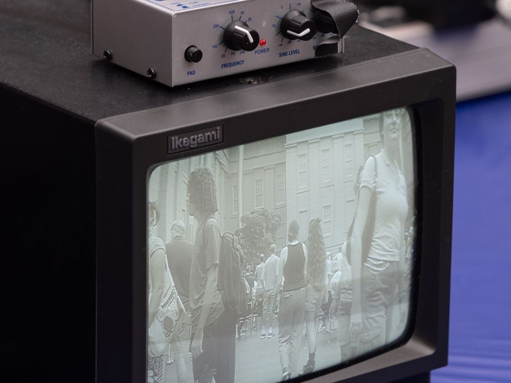 A small black and white tv monitor displays a fuzzy image on the screen. On top of it sits a box with nobs.