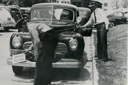 An examiner affixes a &ldquo;driver testing&rdquo; notice ahead of a road test in South Carolina, in the mid-20th century.&nbsp;