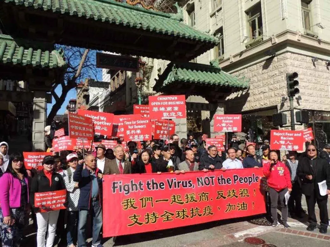 Chinatown protestors carry a banner that says "Fight the Virus, Not the People"