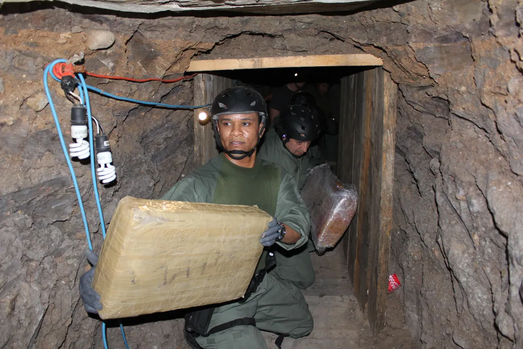 ICE agent removes bundles of marijuana from a tunnel