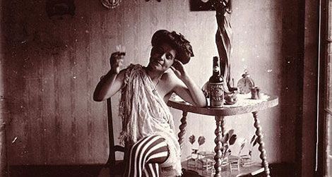 Storyville. Seated woman wearing striped stockings, drinking "Raleigh" Rye.