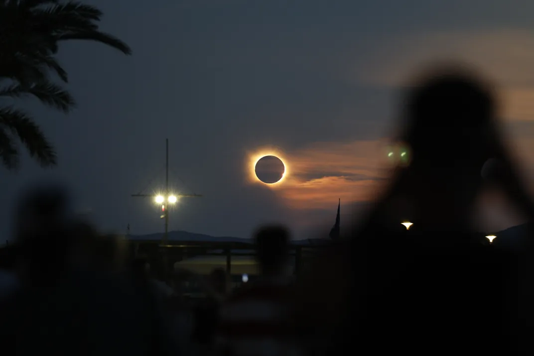 a view of shadows in the foreground and the eclipsed sun hanging low in the sky