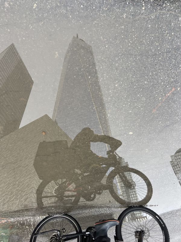 Delivery biker and Freedom Tower reflected in street pool of rain thumbnail