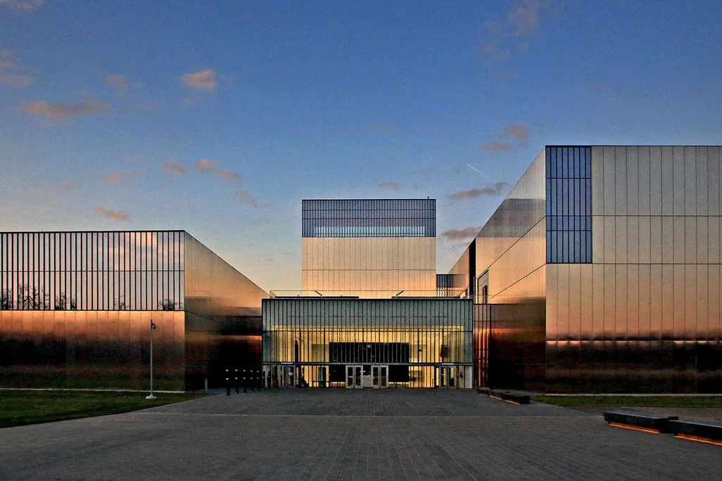 An image of a large, boxy museum with a facade of polished stainless steel and rectangular windows; very modern