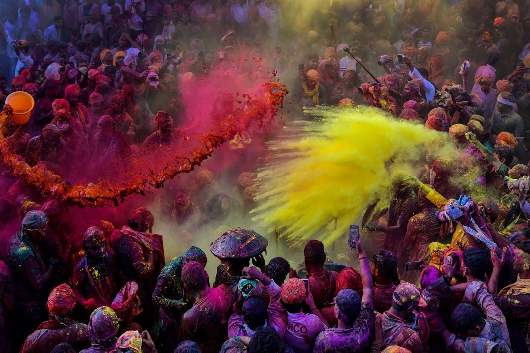 pink and yellow powder is thrown into a large crowd