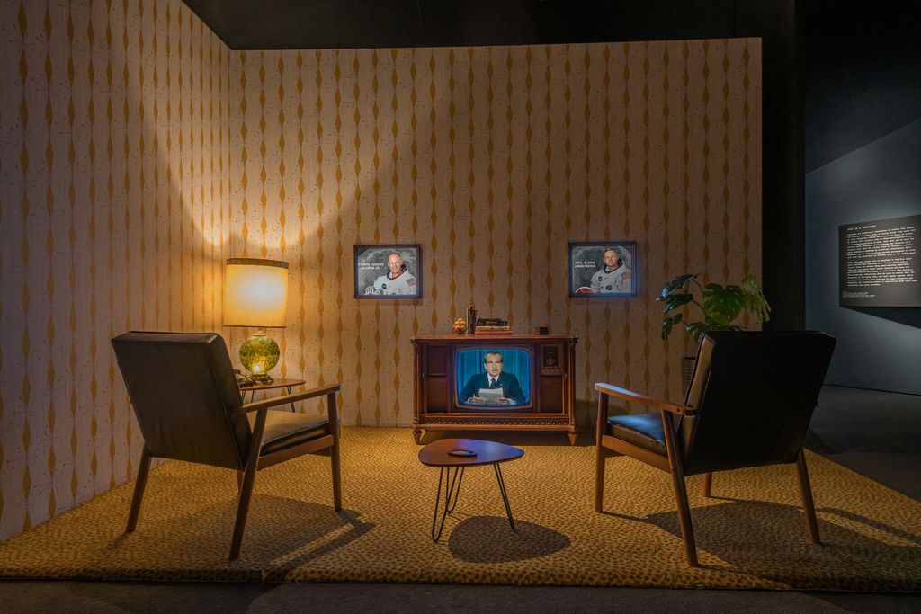museum exhibit with two chairs and an old tv playing nixon footage