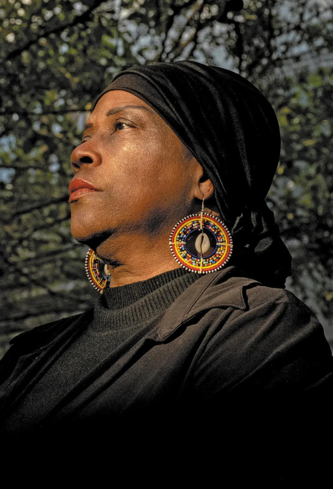 a women wearing a black head wrap stands for a portrait