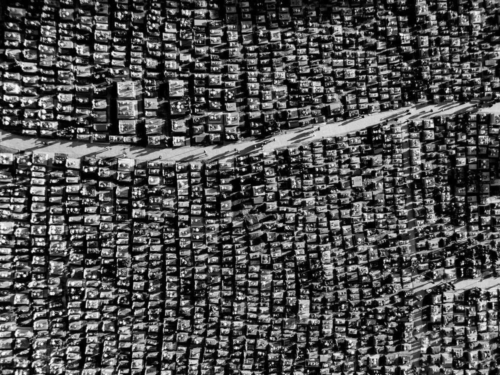 In Poland it is a tradition to visit the graves of deceased loved ones to honor their memory. The image carries symbolic meaning, showing people walking along a path among the graves, their long shadows stretching across the ground.