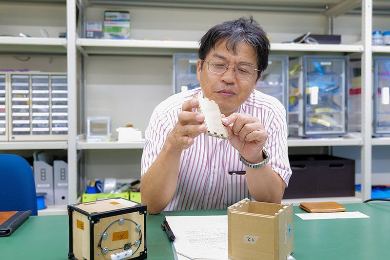 Researcher with wooden satellite