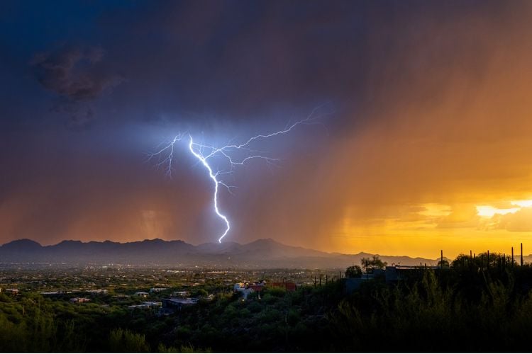 OPENER - Lightning from a summer monsoonal thunderstorm strikes in Tucson just as the sun sets.