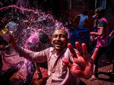 A reveler enjoys a playful and colorful water war in the streets of Jodhpur during the Holi festival.

