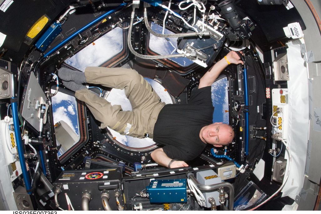 Astronaut Scott Kelly is sideways in the Cupola of the International Space Station
