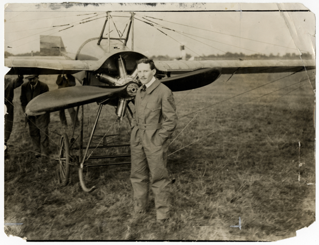 Pilot in a flight suit standing in front of a monoplane
