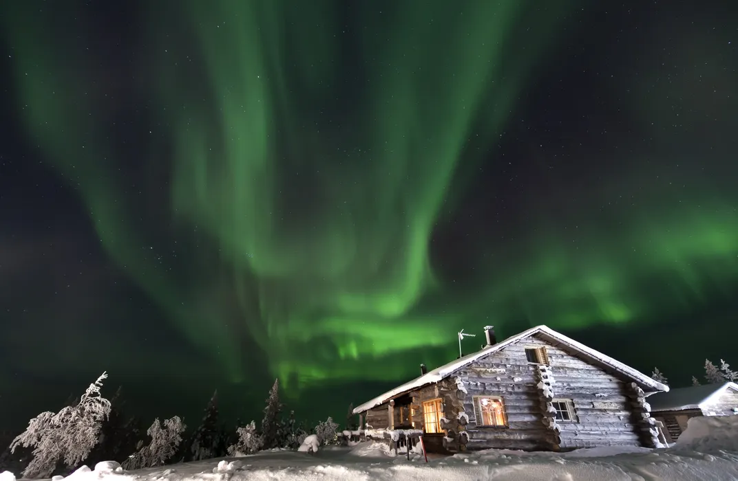 a cabin in the snow with Northern Lights above