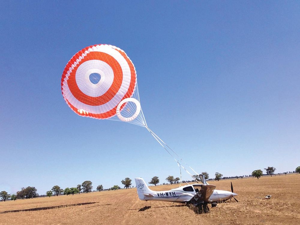 a parachute above a small aircraft only a bit above a field
