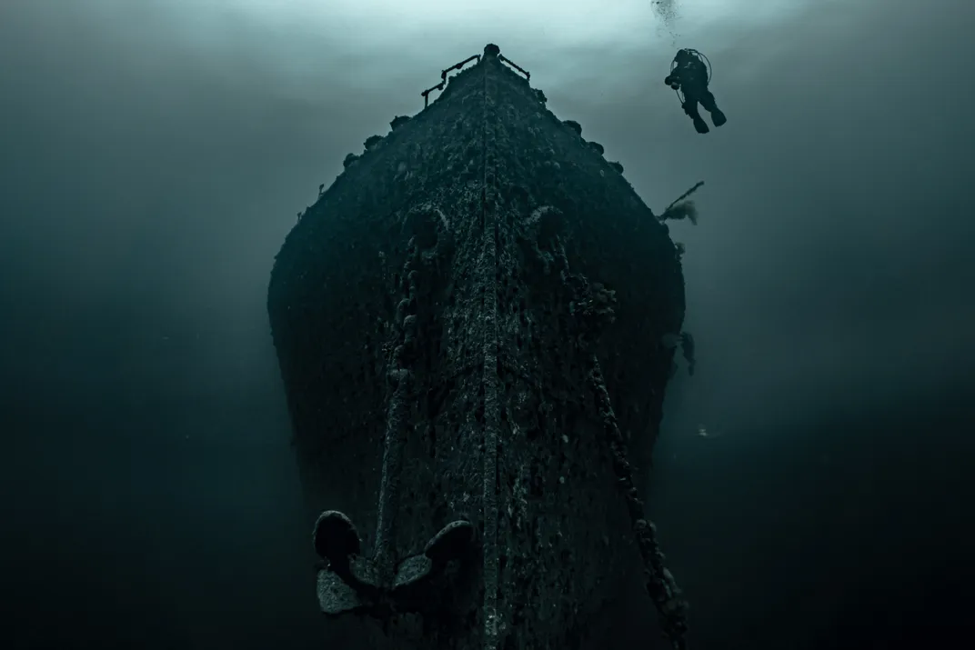A diver hovers over a PLM-27, a World War II ship