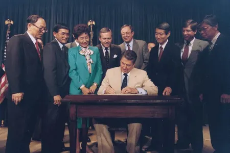 Ronald Reagan signing the Civil Liberties Act of 1988 that apologized for the internment of Japanese American citizens and permanent residents during World War II.