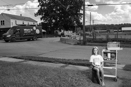 LaBrea Letson, 8, sells lemonade made with bottled water outside her grandmother&rsquo;s home near the derailment site. A van passing by tests the air for hazardous chemicals.