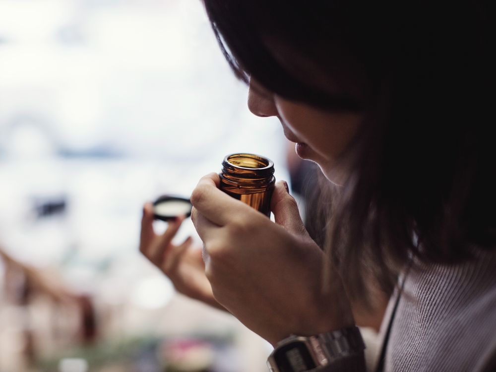 Woman smells open bottle close to her nose