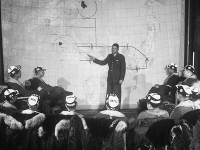 Major Harry B. Bailey, an intelligence officer for the 98th Bomb Group, briefs a B-29 crew on hitting a target in Sinuiju, North Korea with conventional bombs. The city was heavily damaged but has since been rebuilt.
