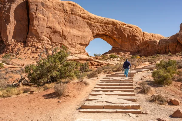 Woman Walking to Rock Arch in Arches NP thumbnail