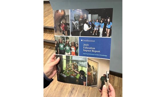 Hard-copy of the FY2023 Smithsonian Education Impact Report held in someone’s hands.