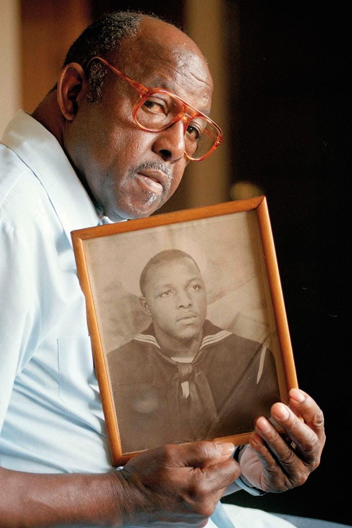 a man holds a portrait of himself while in the Navy