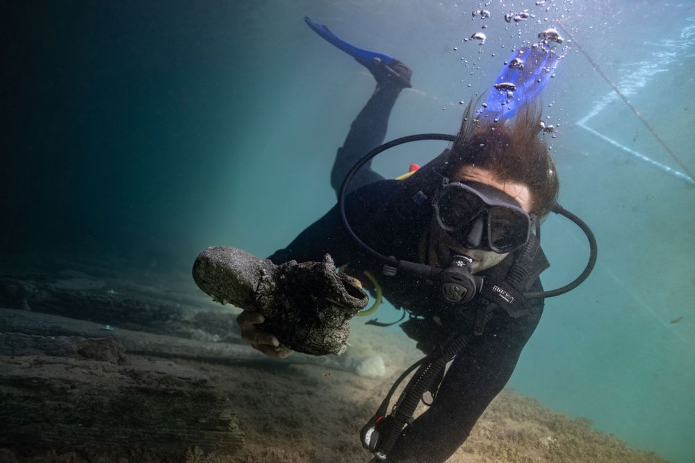 Archaeologist Gino Caspari holds an iron artifact recovered from the shipwrecks.