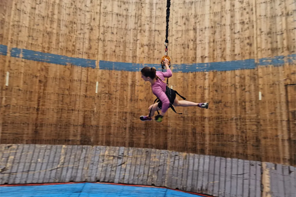 Woman tied to a bungee cord running around a cylindrical wall