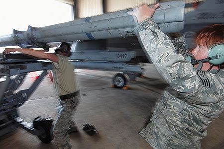 Staff Sergeant Michelle Torrey, right, with Master Sergeant Brett Kitzman load an AIM-120 missile onto an F-16.