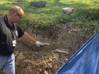 Schuylkill County Deputy Coroner Joe Pothering points to human bones in embankment along Route 61 in Schuylkill Haven, Pennsylvania August 14, 2015. Forensic archaeologists on Friday began excavating a highway embankment in eastern Pennsylvania, looking for more bones believed to be from impoverished victims of the worldwide Spanish flu pandemic in 1918.