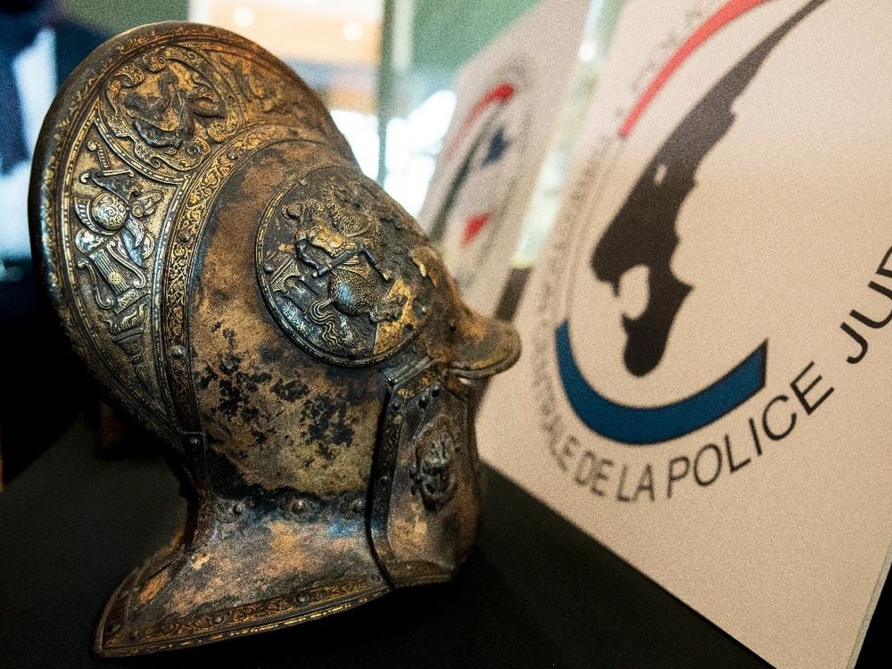 A close up look at an intricately carved helmet, with motifs of flowers, swords, torches and warriors on it