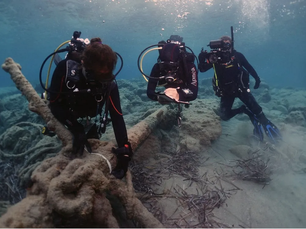Underwater divers holding large anchor