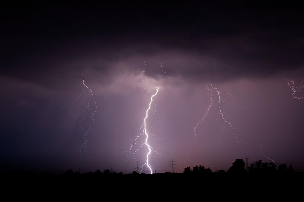 A photo of lightning striking the ground against a moody purple sky