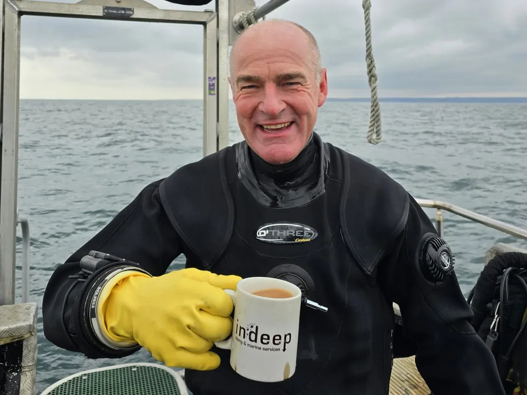 Man in diving suit holding mug