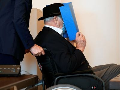 Bruno Dey, a former SS watchman at the Stutthof concentration camp, hides his face behind a folder as he arrives for a hearing in his trial on July 23.