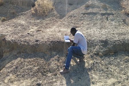 Sylvester Musembi Musyoka, a Kenyan colleague and field crew leader, recording a large mammal fossil bone during a virtual field project to collect fossils in Kenyan excavation sites that were in danger of being damaged by severe weather. (Nzioki Mativo/Smithsonian)