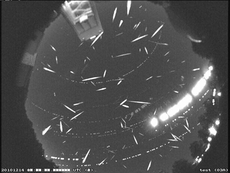 dozens of meteors in the sky in black and white